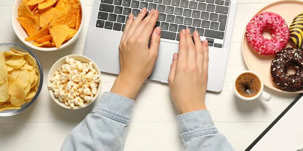 afvallen onder hypnose persoon met laptop en ongezond eten op tafel
