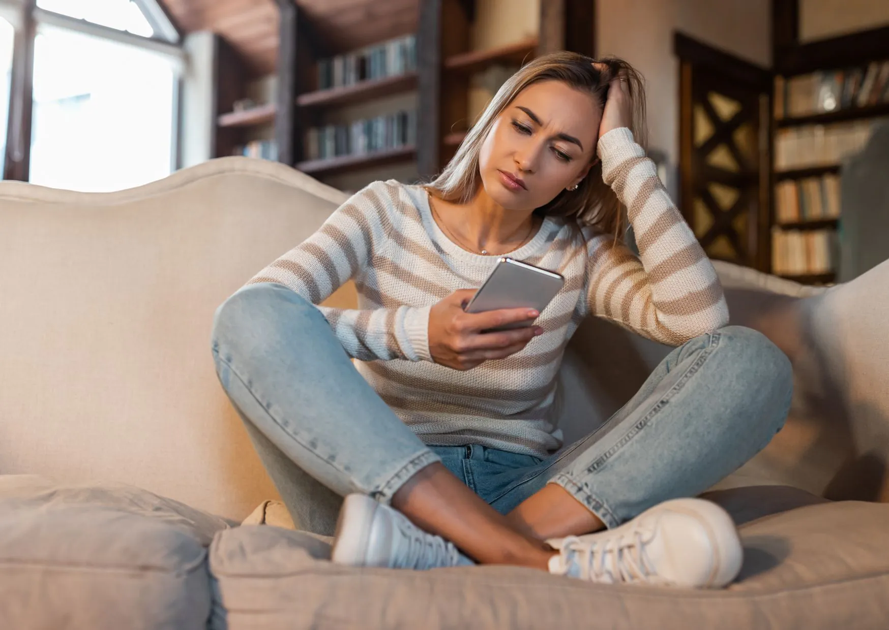 Persoon kijkt twijfelend naar een telefoon, onzeker over de beslissing om hulp te zoeken bij burn-out klachten.